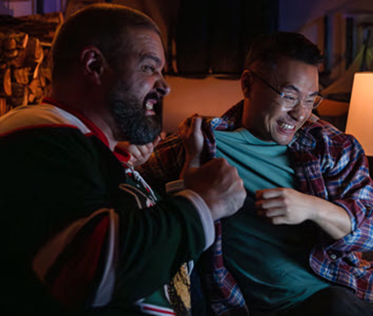 Two men cheering while they watch a hockey game on Eastlink Community TV,