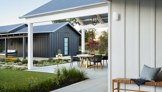 A view of a backyard patio with an eero Outdoor 7 device on the side of the house.